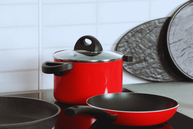 Caçarola e frigideira de jogo de panelas antiaderente vermelho sobre fogão moderno, ilustrando o guia sobre onde comprar panelas com segurança e preço baixo.