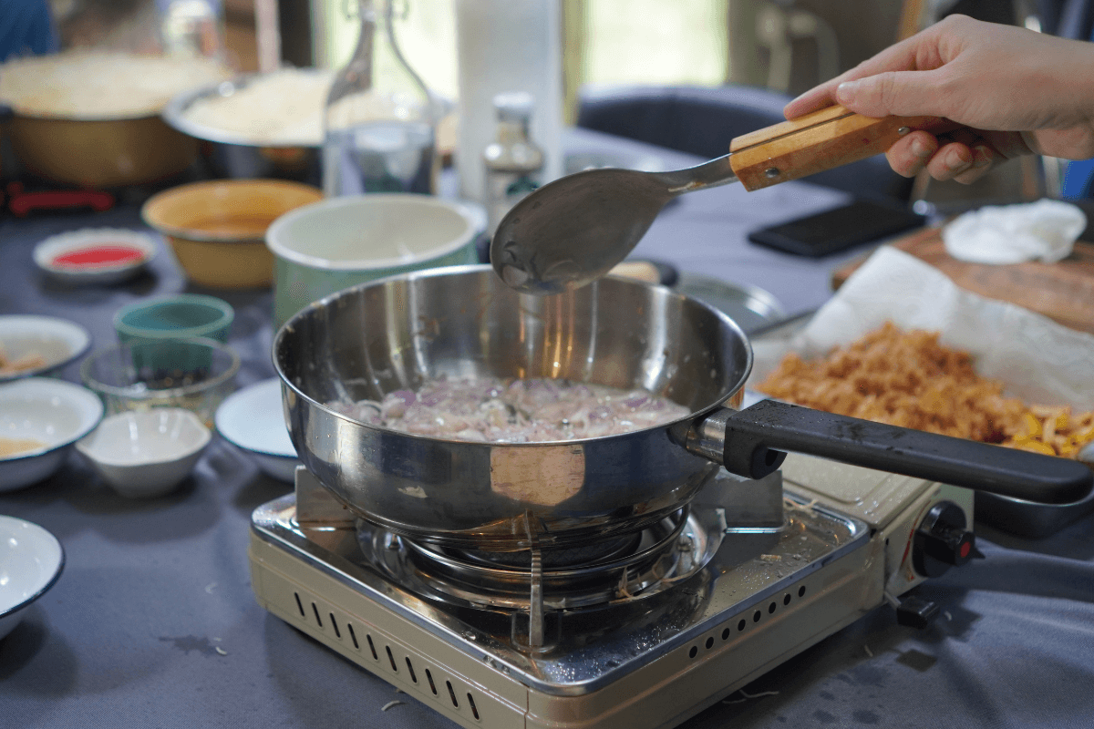 Aço inox é seguro se não estiver riscado Pessoa refogando alimentos em uma frigideira de aço inoxidável usando uma colher de metal, o que pode causar riscos na superfície e comprometer a segurança do material.