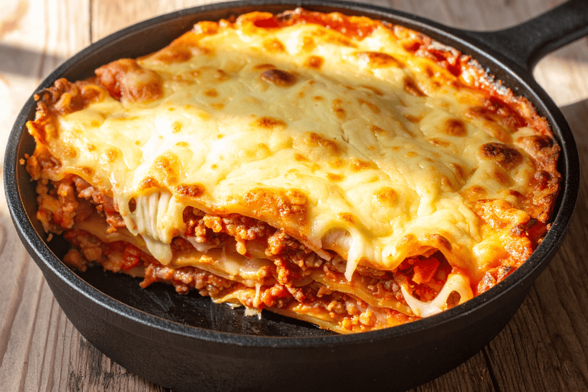 Molhos de tomate na panela de ferro combatem anemia Lasanha com bastante molho de tomate servida diretamente na frigideira de ferro fundido, ilustrando como alimentos ácidos ajudam a soltar o ferro do material para a comida.