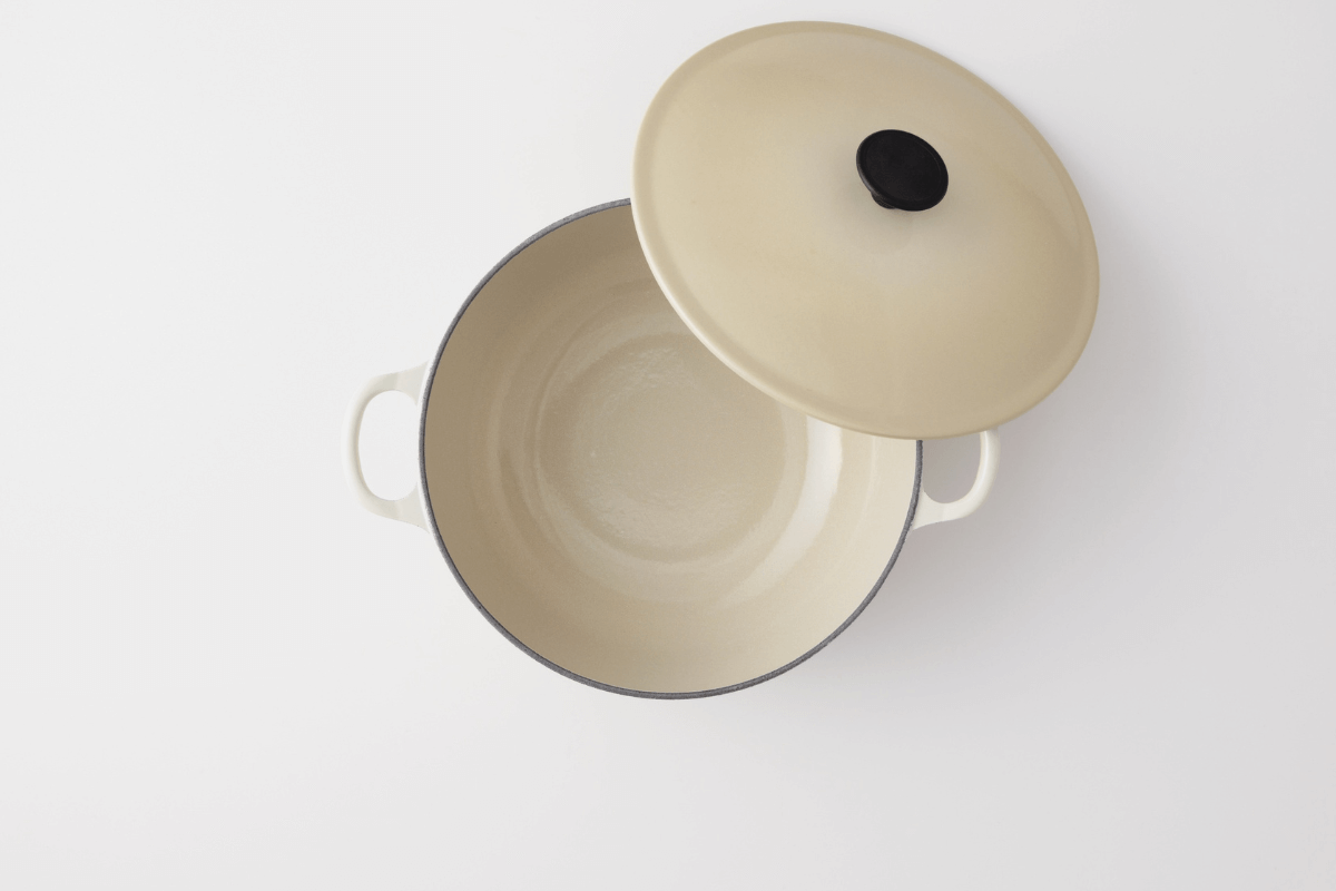 Vista superior de uma caçarola bege com revestimento cerâmico e tampa ao lado, ilustrando a importância de verificar a presença de metais pesados no esmalte vitrificado.