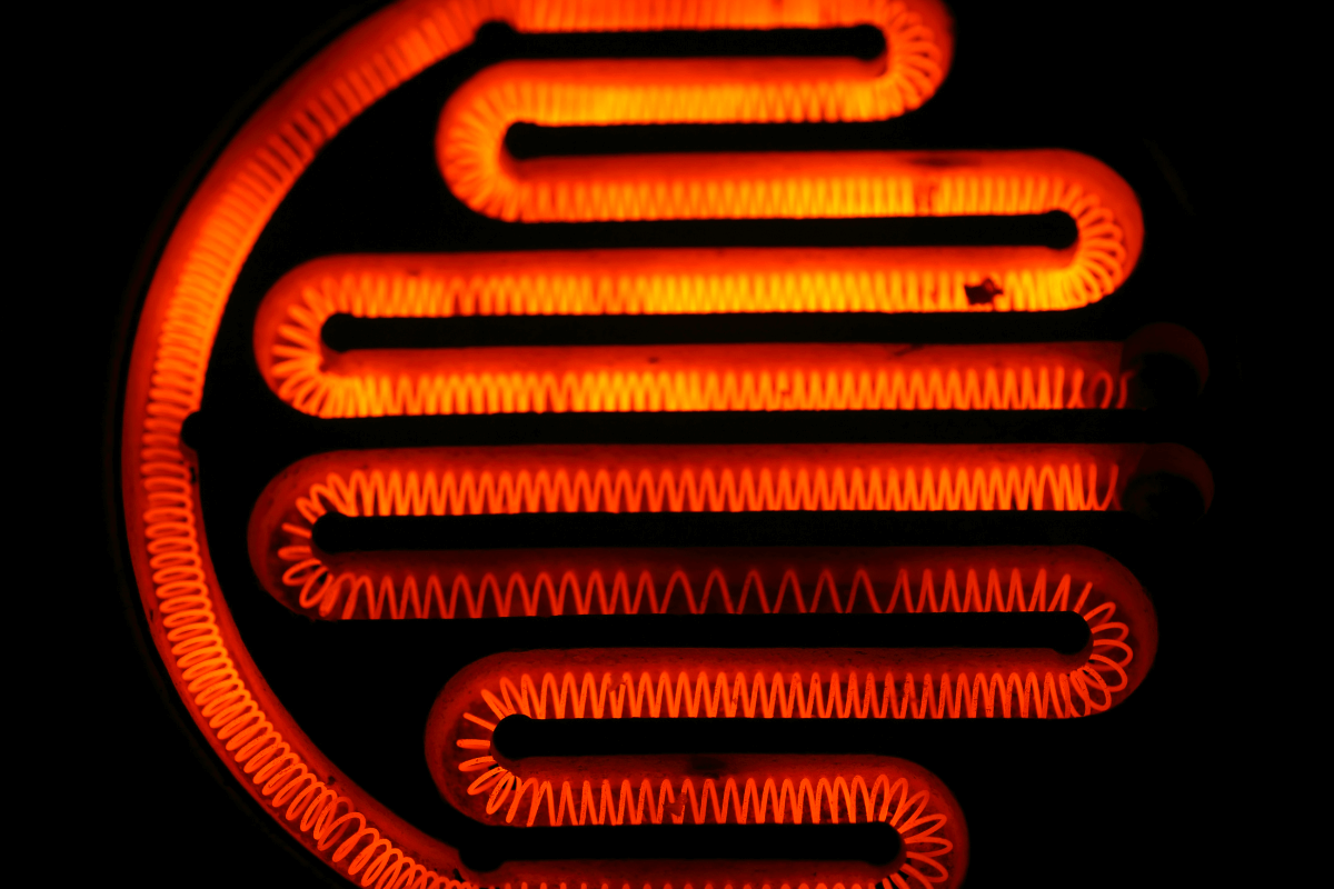 A verdade sobre o consumo de resistências elétricas Close de uma resistência elétrica incandescente brilhando no escuro, ilustrando o funcionamento do aquecimento resistivo.